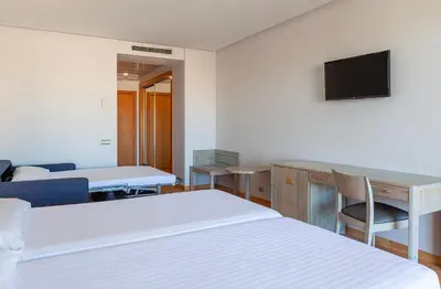 a hotel room with two beds and a television at AGH Canet in Canet de Berenguer