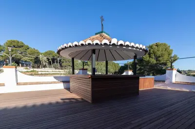 an umbrella sitting on top of a wooden deck at Villa Huerta 1 Manises, jacuzzi, sauna, piscina in Manises