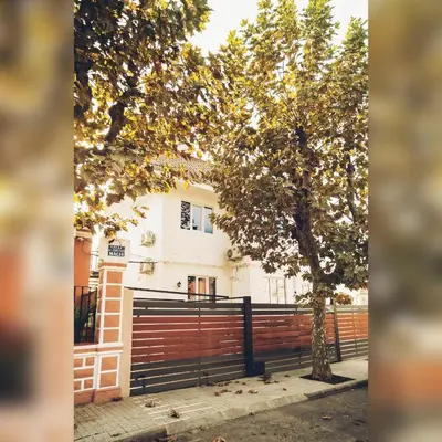 a white house with a fence and a tree at Hostal Orange Vibes in Paterna