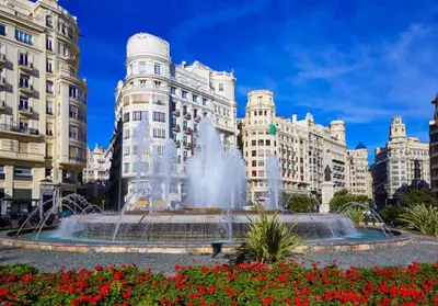 a fountain in front of a building with red flowers at amazing cozy apartment super central in Valencia