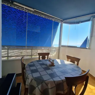 a dining room with a table and chairs and a large window at Precioso apartamento en Cullera, con piscina junto a la playa in Cullera