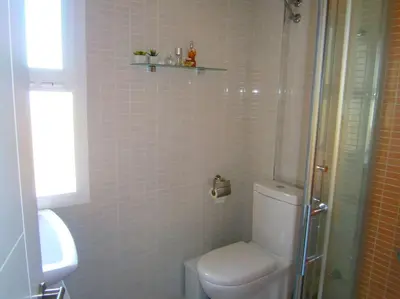 a bathroom with a toilet and a glass shower at Apartamento junto a playa y cerca de campo de golf in El Perellonet