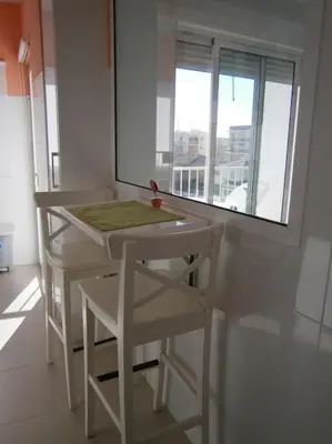 a white table and chairs in a room with a window at Apartamento junto a playa y cerca de campo de golf in El Perellonet
