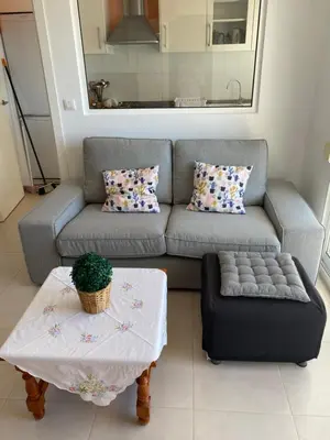 a living room with a couch and a table at Apartamento junto a playa y cerca de campo de golf in El Perellonet