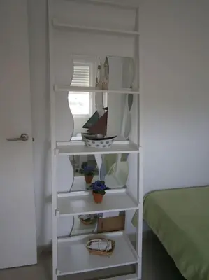 a white book shelf with items on it next to a bed at Apartamento junto a playa y cerca de campo de golf in El Perellonet