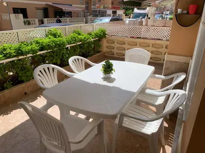 a white table and chairs with a plant on it at Apartamento en la playa in Tavernes de Valldigna