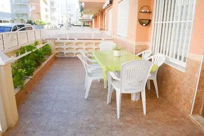 a green table and white chairs on a patio at Apartamento en la playa in Tavernes de Valldigna