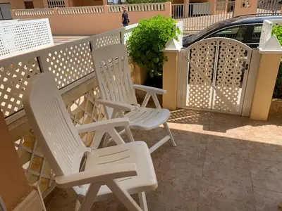 two white chairs sitting on a porch next to a fence at Apartamento en la playa in Tavernes de Valldigna