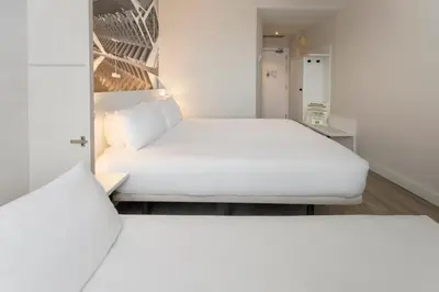 two beds in a small room with white furniture at B&B HOTEL Valencia Arena in Valencia