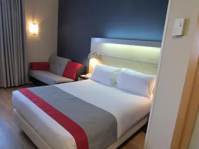 a hotel room with a large bed and a chair at Holiday Inn Express Valencia Bonaire by IHG in Aldaya