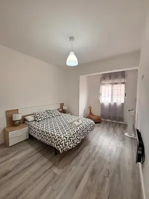 a white bedroom with a bed and wooden floors at Apartamento Sofía II a 500m de la playa in Puerto de Sagunto