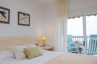 a bedroom with a bed and a balcony with a table and chairs at The Beach Apartment in El Puig