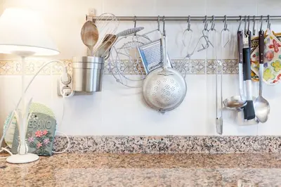 a kitchen counter with utensils hanging on the wall at The Beach Apartment in El Puig