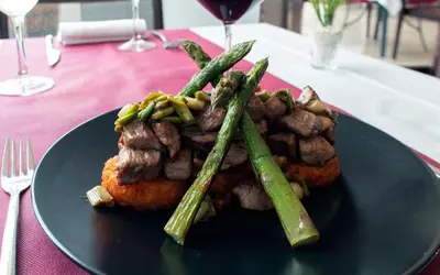 a plate of food with meat and asparagus on a table at Hotel Xon's Valencia in Aldaya