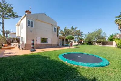 a large yard with a trampoline in front of a house at Casa junto al mar con jardín in Sagunto