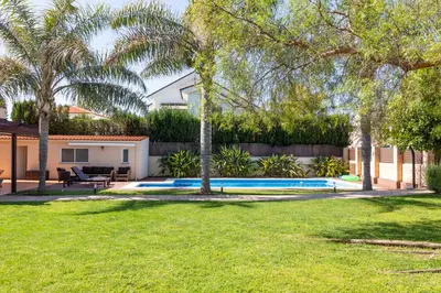 a backyard with a swimming pool and palm trees at Casa junto al mar con jardín in Sagunto