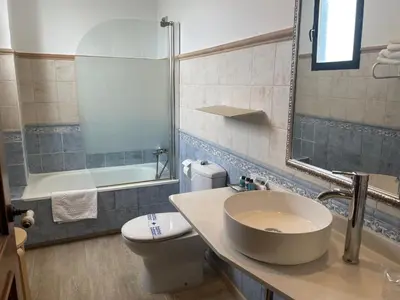 a bathroom with a sink and a toilet and a mirror at Hotel Patilla Ciudad de Requena in Requena