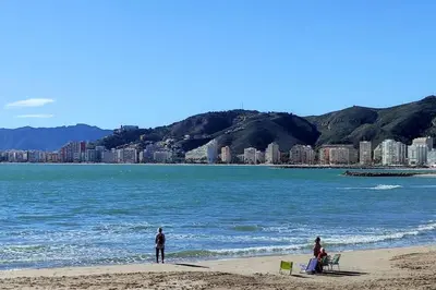 two people on a beach with a city in the background at Precioso apartamento en el Faro de Cullera in Cullera