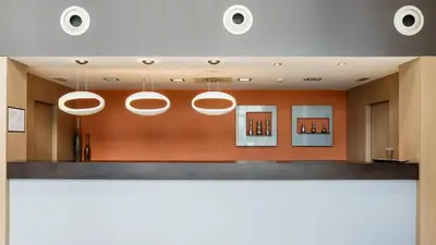 a lobby with orange walls and white lights at Ilunion Aqua 3 in Valencia