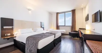 a hotel room with two beds and a window at Ilunion Aqua 4 in Valencia