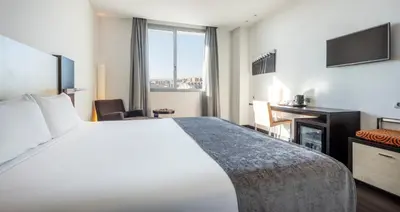 a hotel room with a large bed and a television at Ilunion Aqua 4 in Valencia