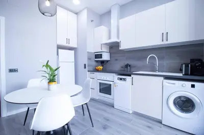 a kitchen with white cabinets and a table and chairs at Patacona by Concept Flats in Valencia