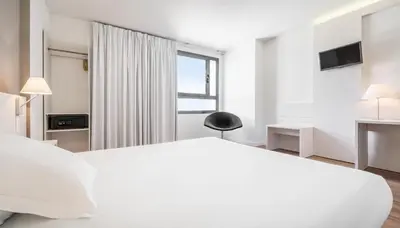 a white bedroom with a large bed and a window at Ilunion Valencia 3 in Valencia