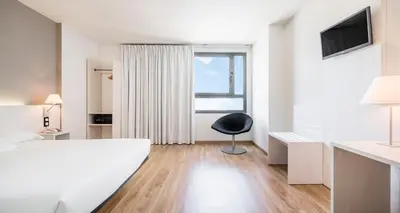 a room with a bed and a chair and a window at Ilunion Valencia 3 in Valencia