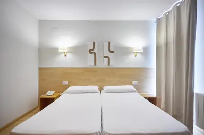 two beds in a room with two lights on the wall at Hotel De Jerica in Jérica