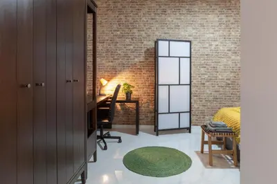a bedroom with a brick wall and a desk with a green rug at Artistic Digital Retreat-Great Location Near Metro in Valencia
