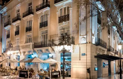 a building with tables and umbrellas in front of it at SH Ingles Boutique Hotel in Valencia