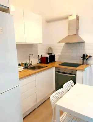 a kitchen with white cabinets and a sink and a table at Apartamento en la playa las arenas +Wifi+AC in Valencia