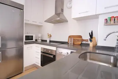 a kitchen with white cabinets and a stainless steel sink at Hogar moderno cerca de Casco Antiguo de Valencia in Valencia