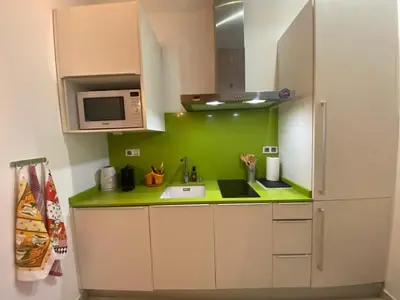 a kitchen with white cabinets and a green wall at Your Valencia Home in Valencia