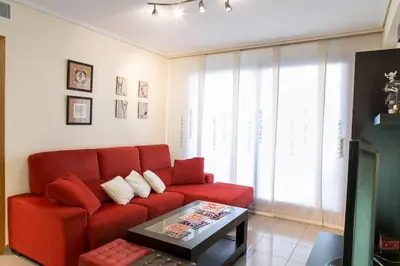 a living room with a red couch and a table at ApartUP Patacona Oriental in Valencia