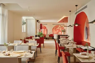 a restaurant with white tables and red chairs at Hospes Palau de La Mar, Valencia, a Member of Design Hotels in Valencia