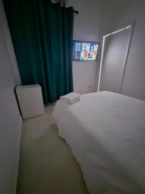 a bedroom with a white bed and a green curtain at Alojame Valencia in Valencia
