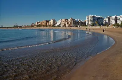 a beach with buildings and people walking on the sand at UIM Mediterraneo M Cristina con garaje Wifi in Puerto de Sagunto