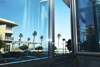 a window with a view of a beach and palm trees at Anka Beach Apartment Patacona in Valencia