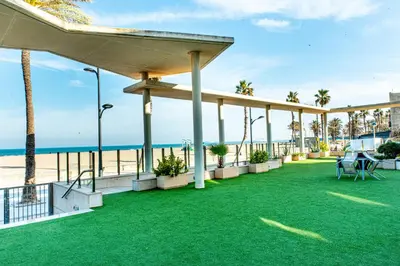 a patio with green grass and the beach at Anka Beach Apartment Patacona in Valencia
