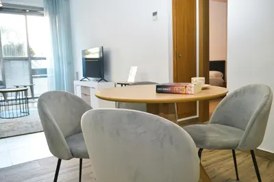 a room with a table and chairs and a table and a book at Anka Beach Apartment Patacona in Valencia