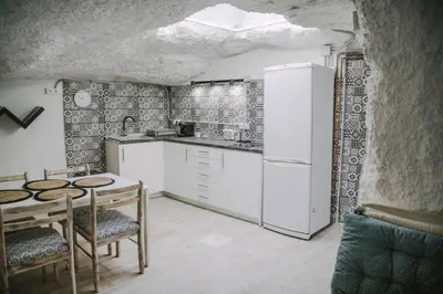 a kitchen with white appliances and a table and chairs at Preciosa casa-cueva con bañera in Paterna