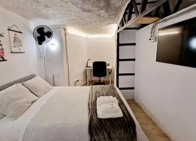 a bedroom with a bed and a tv and a chair at BONITA CASA CUEVA CON JACUZZI in Paterna