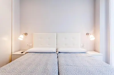 a bedroom with a bed with two lamps on it at Piso en la Playa, Wifi gratis y AC in Valencia