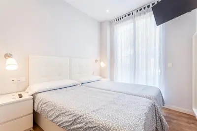 a white bedroom with a bed and a window at Piso en la Playa, Wifi gratis y AC in Valencia