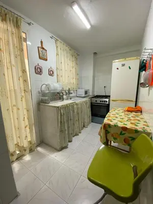a kitchen with a refrigerator and a table with a green chair at Casa en Puerto de Sagunto. Playa in Canet de Berenguer
