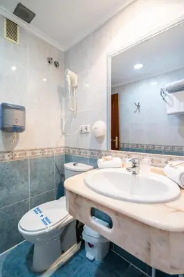 a bathroom with a sink and a toilet and a mirror at Hotel Beleret in Valencia