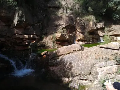 a person standing next to a waterfall in a rocky mountain at Acogedora y moderna casa en pueblo in Serra