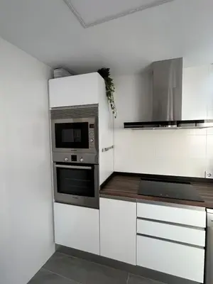 a kitchen with white cabinets and a microwave at Acogedora y moderna casa en pueblo in Serra