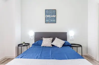 a bedroom with a bed with blue sheets and two tables at Apartamento nuevo cerca de la playa y del centro in Valencia